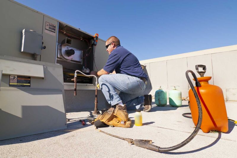 HVAC technician on a rooftop performing maintenance on equipment